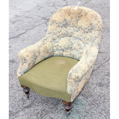 100 - An antique upholstered armchair with turned wooden legs and brass and ceramic castors