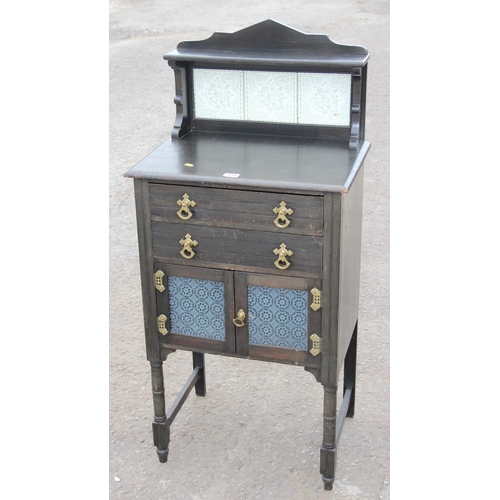 130 - An unusual antique ebonised cabinet with tile back and 2 drawers, the drawers containing 2 vintage g... 