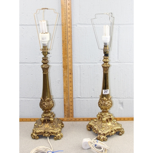 257 - A large pair of gilt metal lamps in the Rococo style decorated with Putto masks, with pink shades