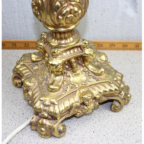 257 - A large pair of gilt metal lamps in the Rococo style decorated with Putto masks, with pink shades