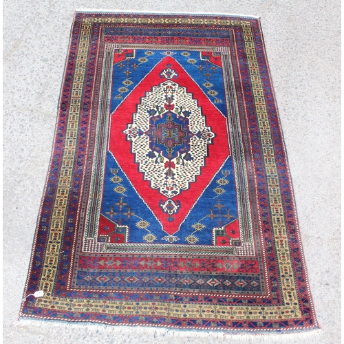 211 - A vintage hand knotted blue ground rug with large red diamond shaped medallion and various geometric... 