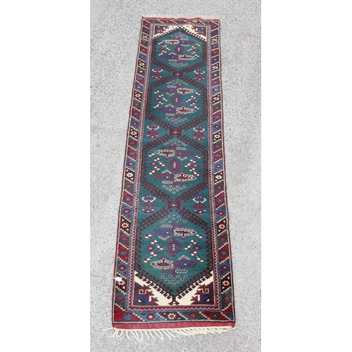 213 - A long vintage hand knotted runner rug of green ground with medallions, approx 310cm x 80cm