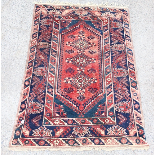 215 - A vintage hand knotted rug of red and blue ground with geometric border, approx 200cm x 130cm