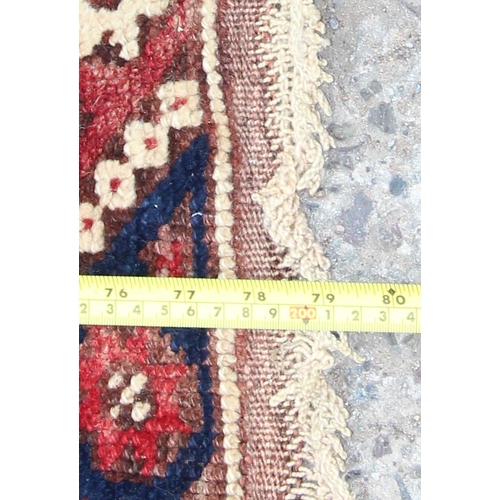 215 - A vintage hand knotted rug of red and blue ground with geometric border, approx 200cm x 130cm