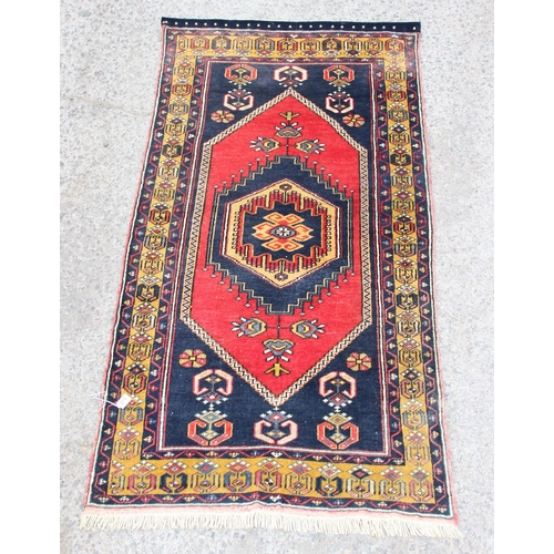 216 - A vintage hand knotted rug of blue ground with large central red medallion and yellow border, approx... 