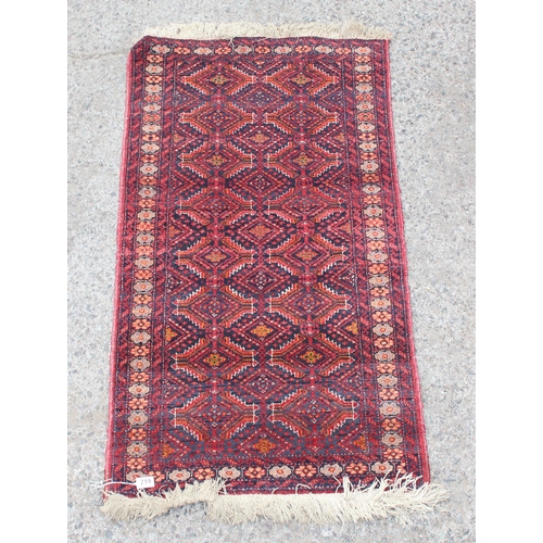 219 - A vintage hand knotted rug of red ground decorated with geometric gul, approx 140cm x 70cm