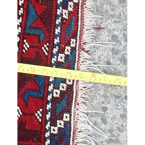 221 - A decorative vintage hand knotted rug of red and blue ground with various geometric patterns, approx... 