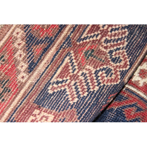 215 - A vintage hand knotted rug of red and blue ground with geometric border, approx 200cm x 130cm