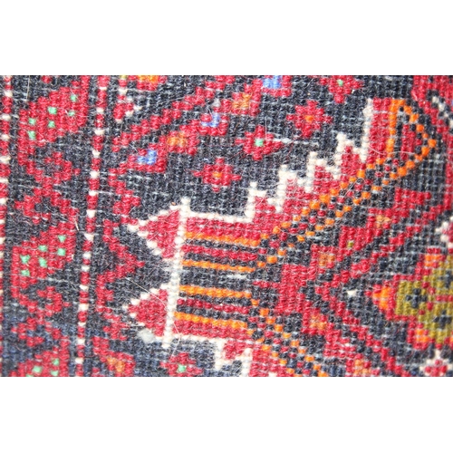 219 - A vintage hand knotted rug of red ground decorated with geometric gul, approx 140cm x 70cm