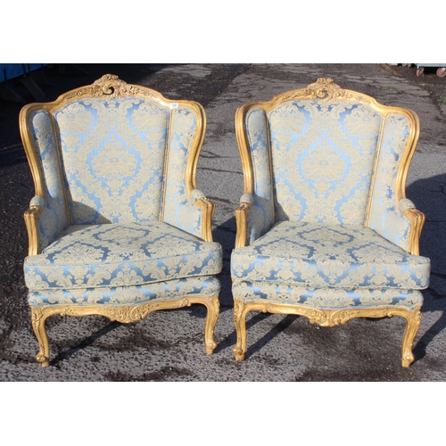 100 - A pair of French style high backed armchairs with carved giltwood frame and blue & gold upholstery, ... 