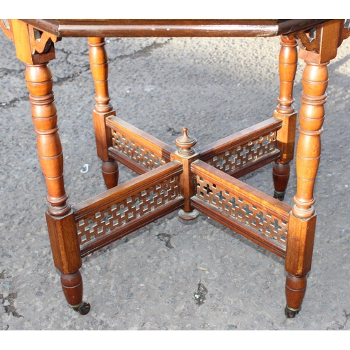 142 - A late Victorian mahogany octagonal table standing on brass and ceramic castors with Aesthetic Movem... 