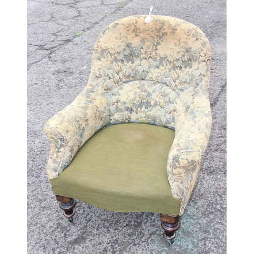 149I - An antique upholstered armchair with turned wooden legs and brass and ceramic castors