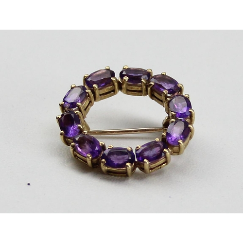 1230 - 9ct gold and amethyst brooch set in a circular pattern, hallmarked for 9ct gold, approx 4.99g gross