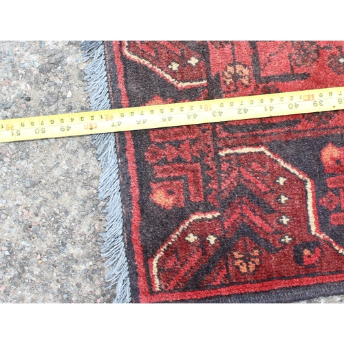 166 - A small handmade red and black ground rug, likely Turkish in origin, approx 120cm x 80cm