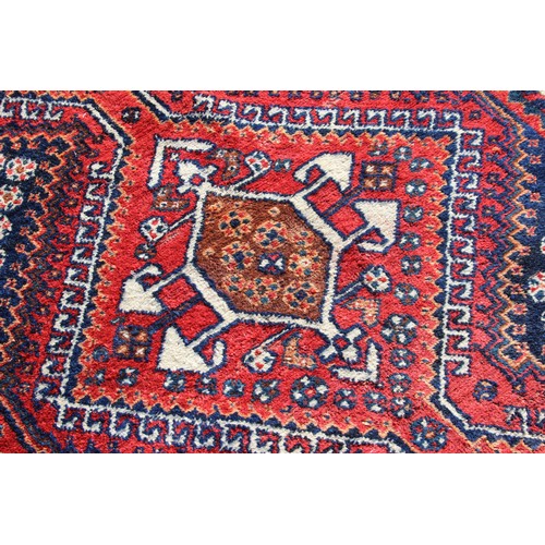 153 - A vintage red and blue ground hand made rug with 3 diamond medallions, approx 240cm 130cm