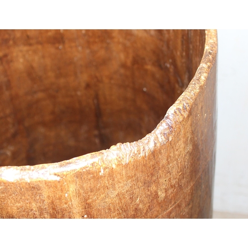 119 - A large wooden bucket on short legs, seeming carved from one piece of wood, likely African, approx 8... 