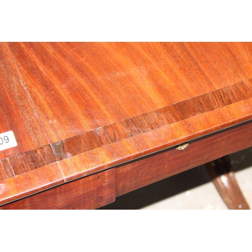 109 - An antique mahogany sofa table with hidden drawers and drop ends with crossbanded decoration