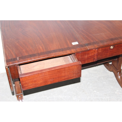 109 - An antique mahogany sofa table with hidden drawers and drop ends with crossbanded decoration