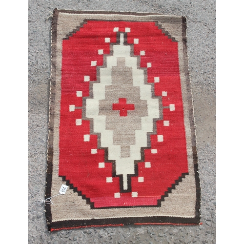 205 - A vintage red ground rug with diamond medallion, approx 107cm x 63cm