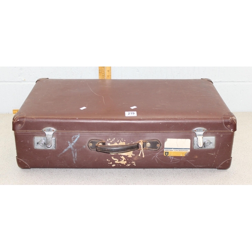 219 - A vintage brown suitcase containing linen and lace, other fabrics etc