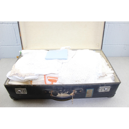 220 - A vintage blue suitcase containing linen and lace, other fabrics etc