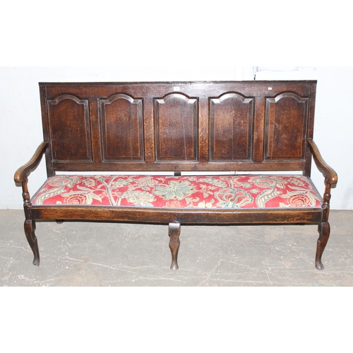 6 - An 18th century oak hall bench, the low rectangular back with 5 panels and scroll arms above a long ... 