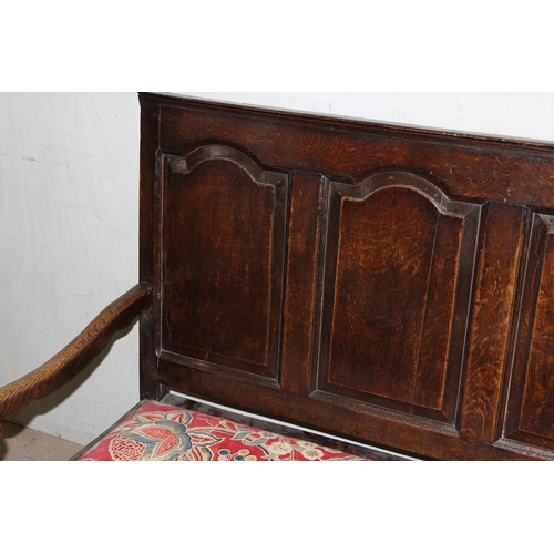 6 - An 18th century oak hall bench, the low rectangular back with 5 panels and scroll arms above a long ... 