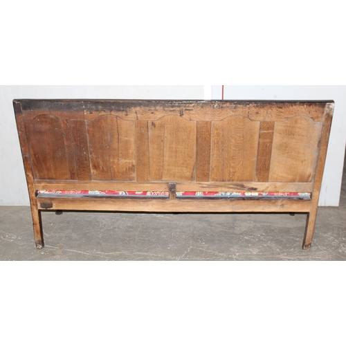 6 - An 18th century oak hall bench, the low rectangular back with 5 panels and scroll arms above a long ... 