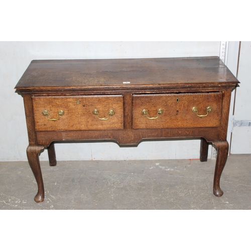 9 - An 18th century small oak sideboard with 2 deep drawers and brass handles, standing on cabriole legs... 