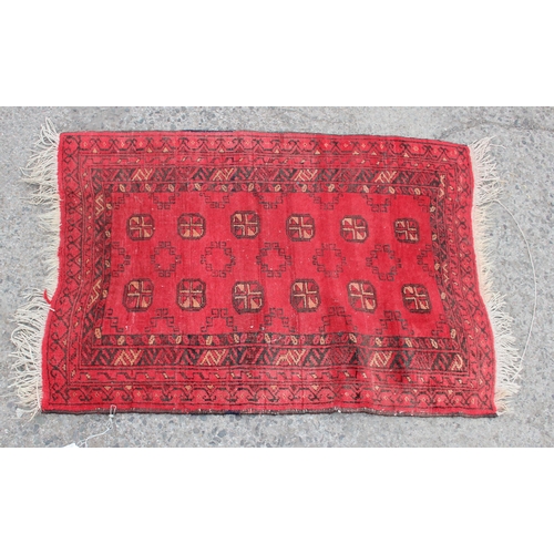 229 - A vintage red ground Afghan rug decorated with gul, approx 110cm long