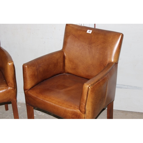 88 - A pair of tan leather carver armchairs with wooden legs, likely John Lewis