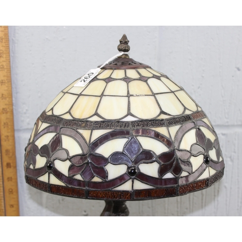 260 - A Tiffany style table lamp with leaded glass shade and a bronzed metal base formed as a classical fe... 