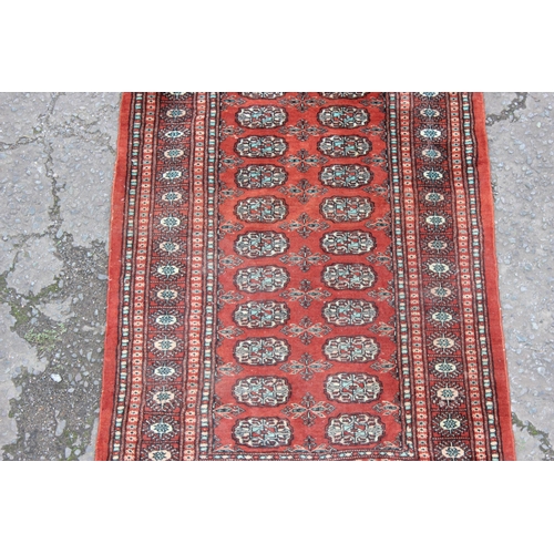 213 - Hand tied Pakistani Bokhara red ground rug with 22 gul central panel