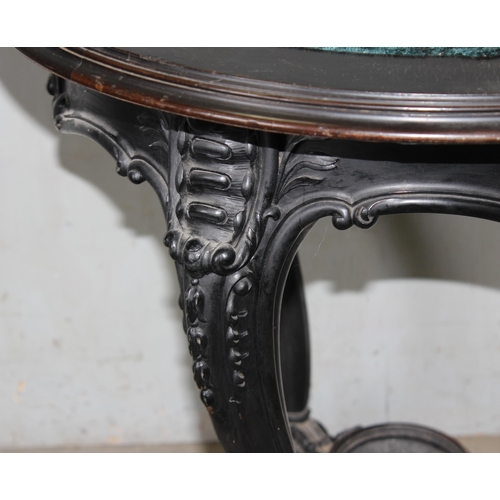 26 - A 19th century Continental ebonised and profusely carved round topped table with green fabric top in... 