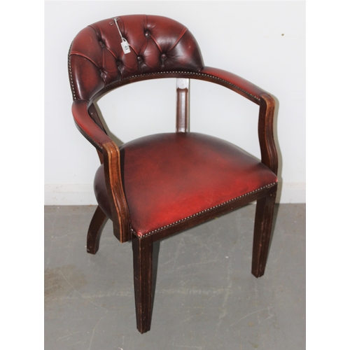 49 - An ox-blood red button backed armchair or desk chair with metal studded decoration