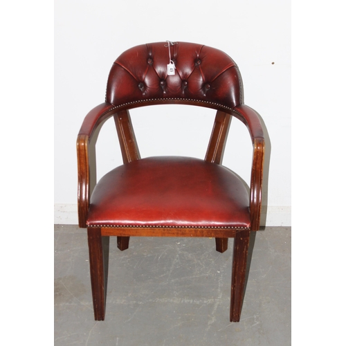 49 - An ox-blood red button backed armchair or desk chair with metal studded decoration