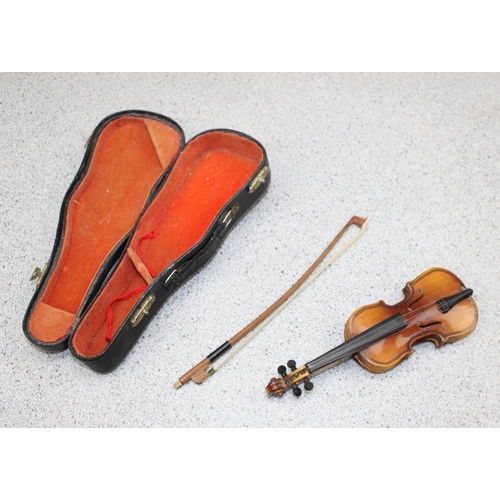 670 - Wooden bodied four string Ukulele and a scale model miniature violin and bow in fitted case. (2 item... 