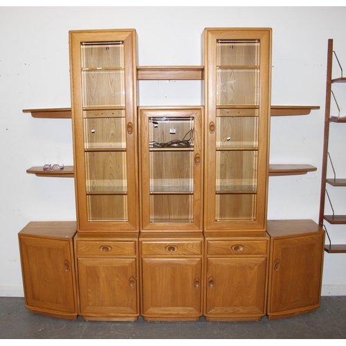 134 - A large blonde Ercol modular type wall unit comprising of shelves around 3 glazed display cabinets, ... 