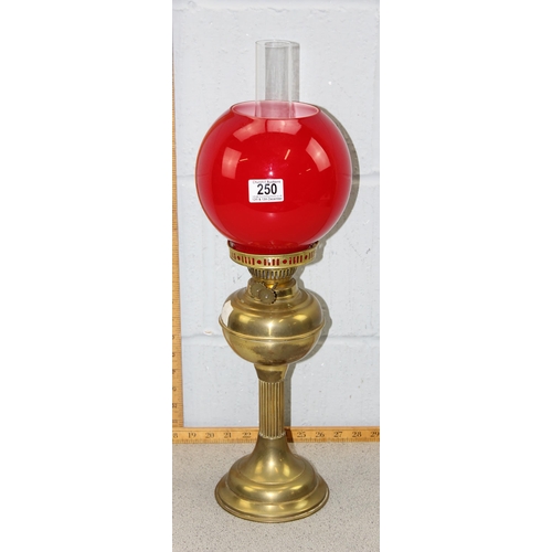 250 - An antique brass column table lamp with red glass shade