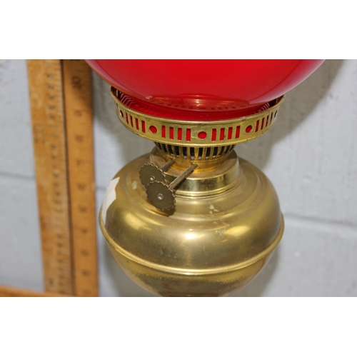 250 - An antique brass column table lamp with red glass shade