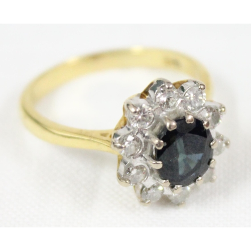 1114 - An 18ct gold ring set with large central blue sapphire surrounded by 10 diamonds, marked for London ... 