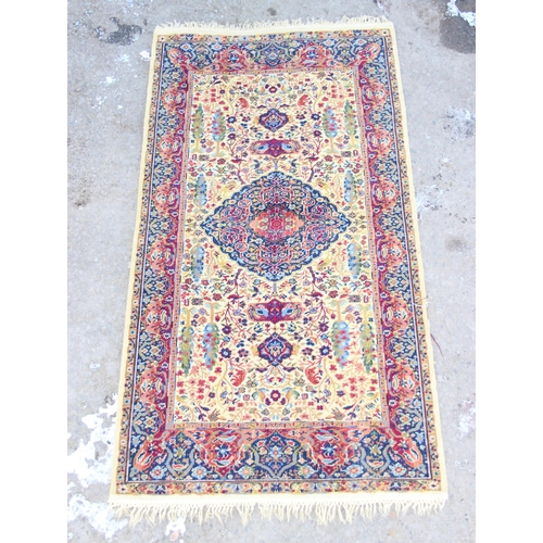 204 - A decorative rug, gold ground with blue arabesque border, approx 184cm x 92cm