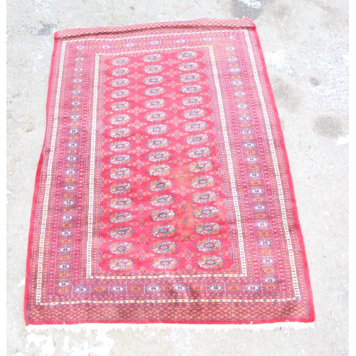 207 - A large vintage red ground rug decorated with 3 lines of 16 gul, approx 185cm x 130cm