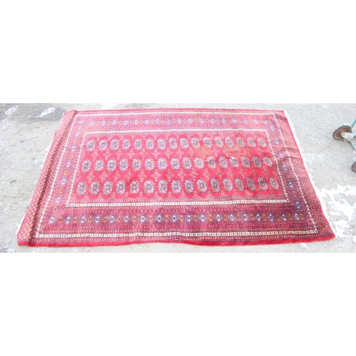 207 - A large vintage red ground rug decorated with 3 lines of 16 gul, approx 185cm x 130cm