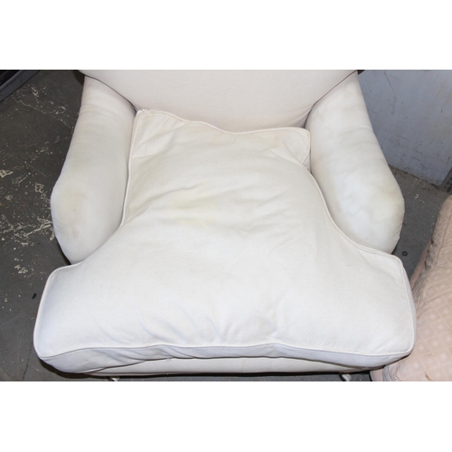 100 - In the style of Howard & Sons, low seated cream sofa chair with associated foot stool, purchased by ... 