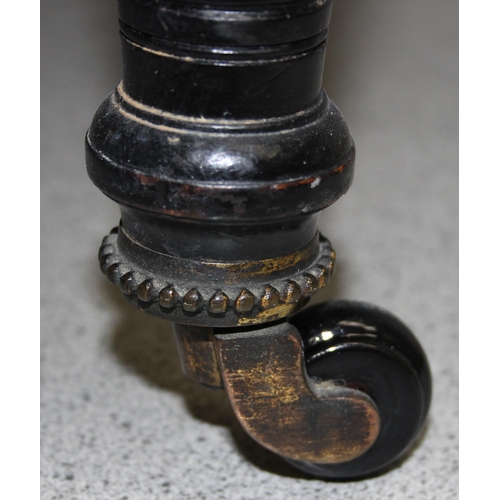 105 - An antique button backed bedroom tub chair with turned ebonised legs and brass and ceramic castors m... 