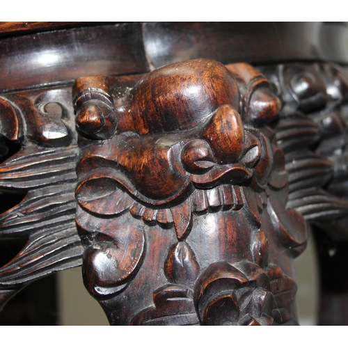 106 - A Chinese carved hardwood jardinière stand with red marble inset top, the legs profusely carved with... 