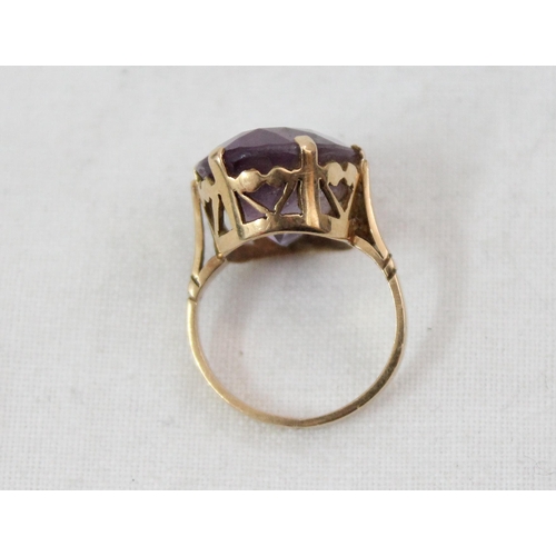 1157 - An 18ct yellow gold ring mounted with a large cut purple stone, unmarked but XRF tested as 18ct gold... 