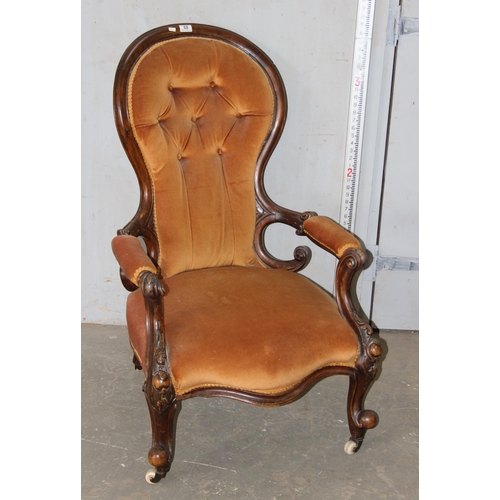 68 - A 19th century button backed low armchair with deeply carved mahogany frame and brass and ceramics c... 