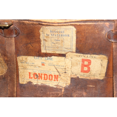 206 - A large early 20th century leather travelling case or luggage bag with labels